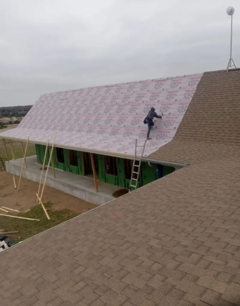 Worker preparing underlayment for a metal roof installation in Thomaston